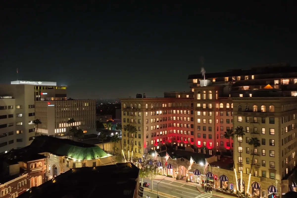 Aerial view of a lit hotel building and street at night in Beverly Hills